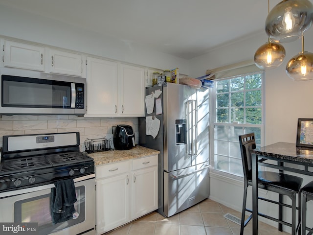 kitchen featuring decorative backsplash, stainless steel appliances, light tile patterned floors, decorative light fixtures, and white cabinets