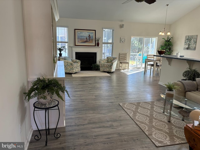 living room featuring ceiling fan with notable chandelier, hardwood / wood-style flooring, and vaulted ceiling