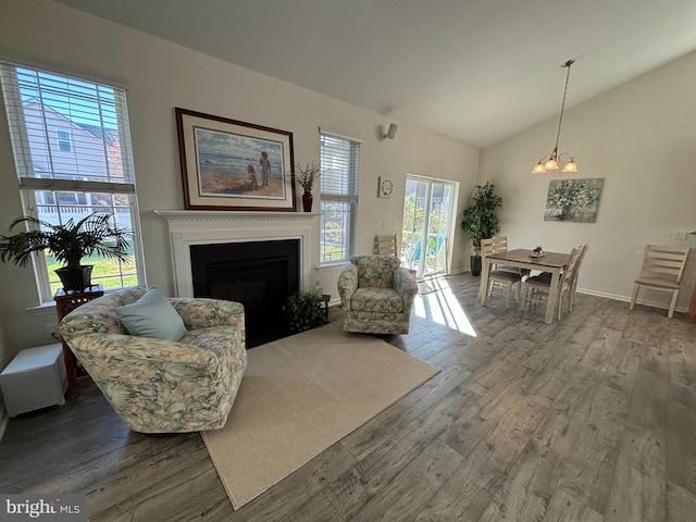 living room with a chandelier, wood-type flooring, and vaulted ceiling