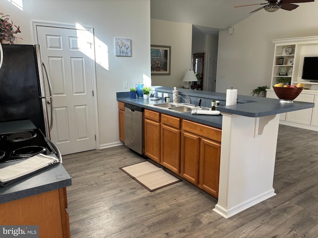 kitchen with a kitchen bar, stainless steel dishwasher, dark wood-type flooring, sink, and fridge