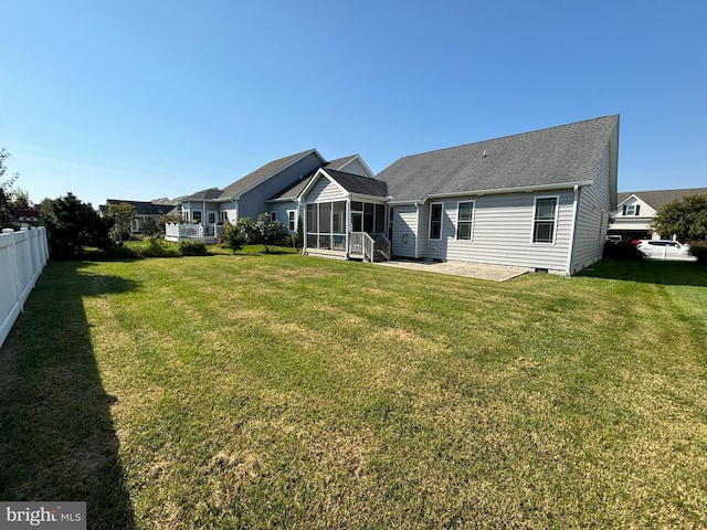 back of house featuring a lawn, a sunroom, and a patio