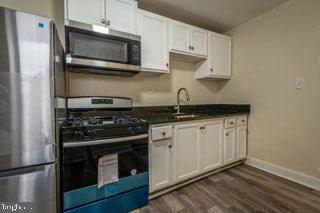 kitchen with white cabinetry, stainless steel appliances, and dark hardwood / wood-style flooring