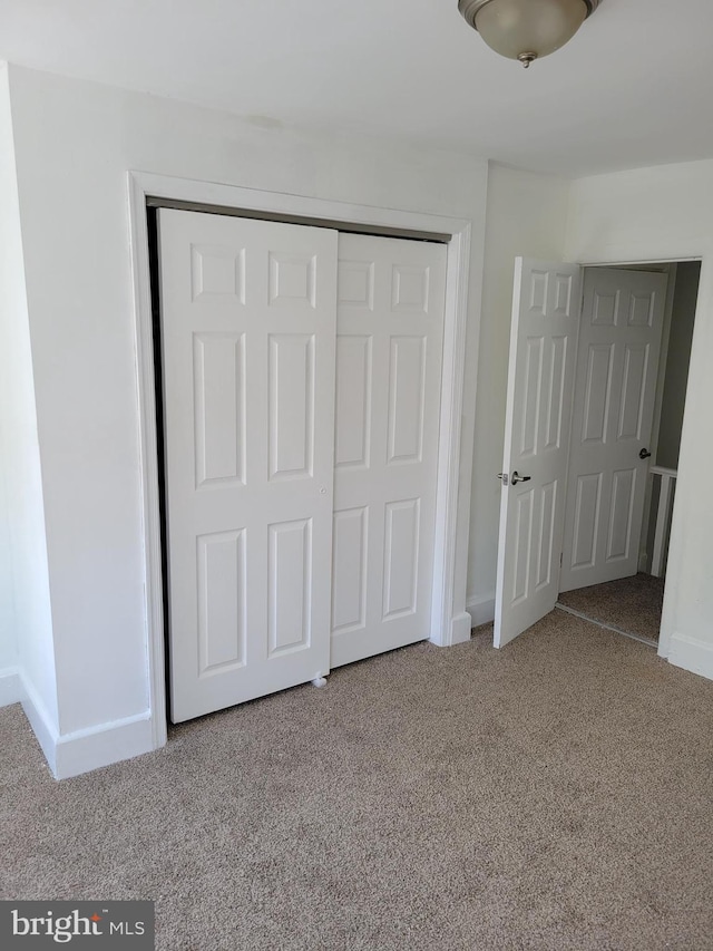 unfurnished bedroom featuring light carpet and a closet