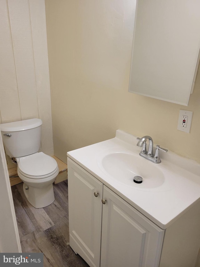 bathroom with wood-type flooring, vanity, and toilet