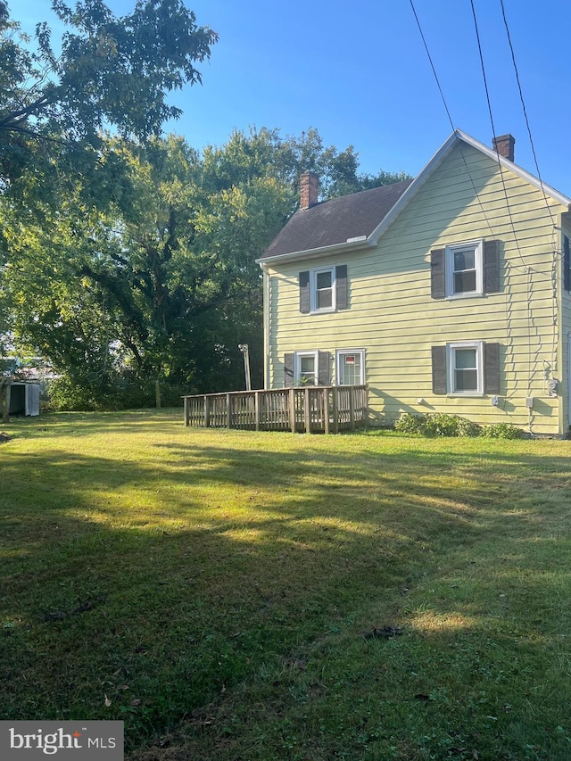 711 6th St, Pocomoke City, MD 21851 - back of property with a chimney, a lawn, and a wooden deck