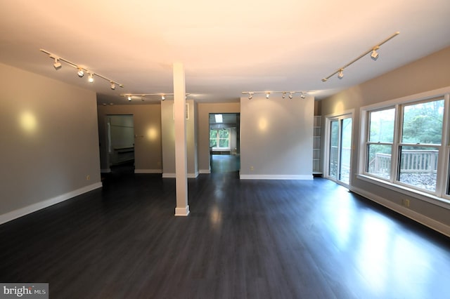 empty room with dark hardwood / wood-style floors and track lighting