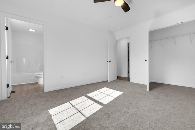 unfurnished bedroom with ensuite bathroom, ceiling fan, carpet floors, and a closet