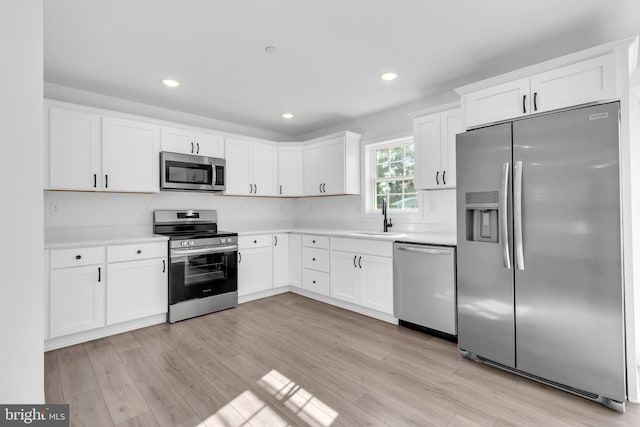 kitchen featuring light hardwood / wood-style floors, appliances with stainless steel finishes, sink, and white cabinetry