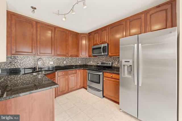 kitchen with decorative backsplash, sink, light tile patterned flooring, dark stone counters, and appliances with stainless steel finishes