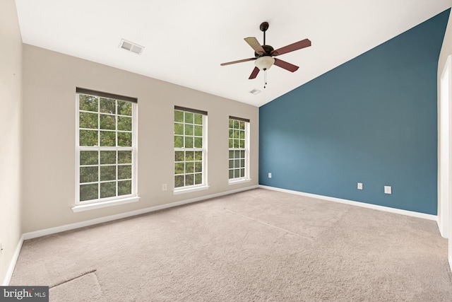 carpeted empty room with ceiling fan, a wealth of natural light, and vaulted ceiling