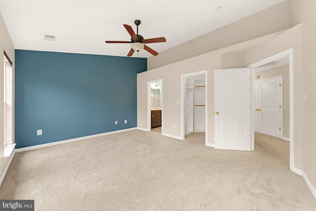 unfurnished bedroom with ceiling fan, light colored carpet, a spacious closet, a closet, and vaulted ceiling