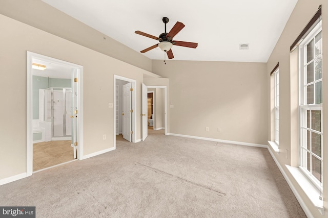 unfurnished bedroom featuring ceiling fan, vaulted ceiling, ensuite bathroom, and light carpet