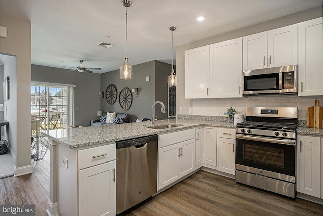 kitchen with sink, appliances with stainless steel finishes, decorative light fixtures, and white cabinets