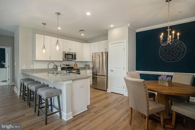 kitchen featuring light hardwood / wood-style flooring, kitchen peninsula, stainless steel appliances, pendant lighting, and white cabinets