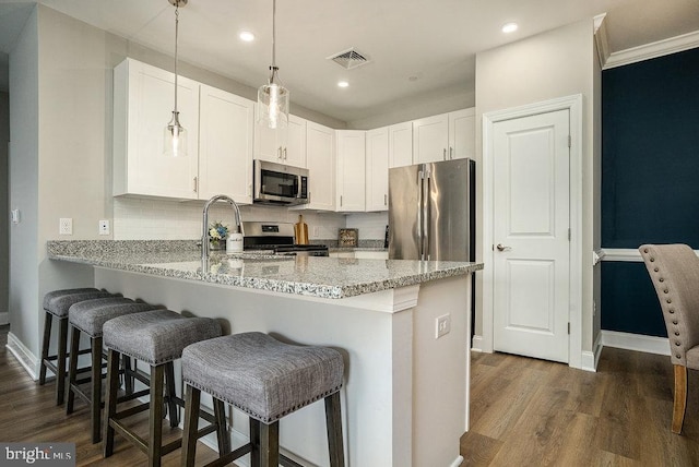 kitchen with kitchen peninsula, white cabinetry, light stone countertops, dark hardwood / wood-style floors, and stainless steel appliances