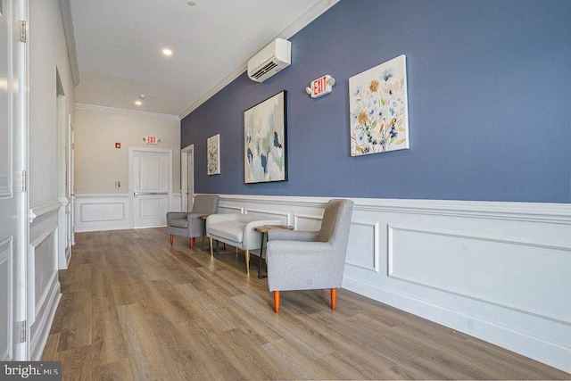 living area with crown molding, a wall mounted AC, and wood-type flooring