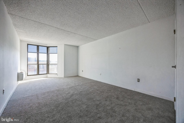 unfurnished room with a textured ceiling, baseboards, radiator heating unit, and carpet floors