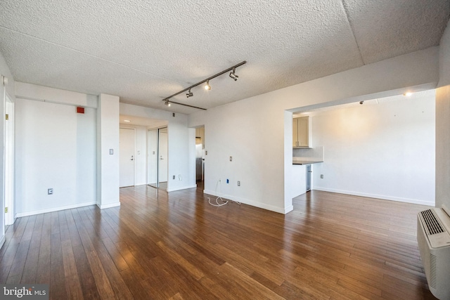 spare room with track lighting, a textured ceiling, wood finished floors, and baseboards