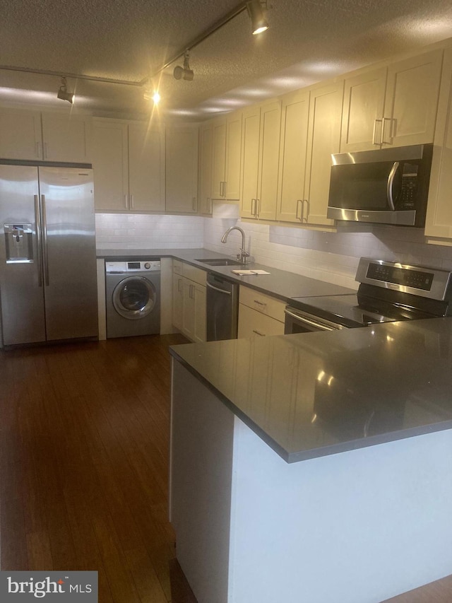 kitchen featuring washer / clothes dryer, sink, dark hardwood / wood-style flooring, stainless steel appliances, and track lighting