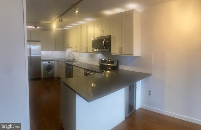 kitchen with a breakfast bar area, kitchen peninsula, stainless steel appliances, and washer / clothes dryer