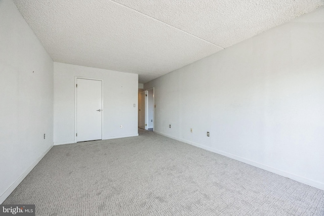 spare room featuring baseboards, light carpet, and a textured ceiling