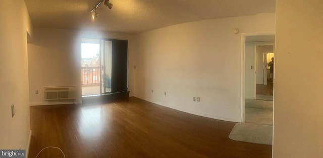 unfurnished room featuring rail lighting, hardwood / wood-style flooring, a wall mounted AC, and a textured ceiling