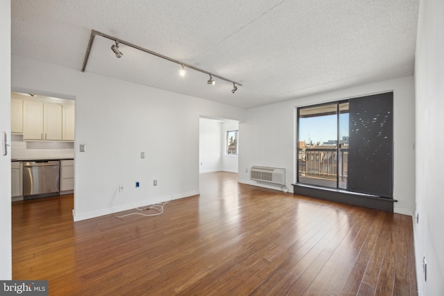 unfurnished living room featuring rail lighting, a textured ceiling, and wood finished floors
