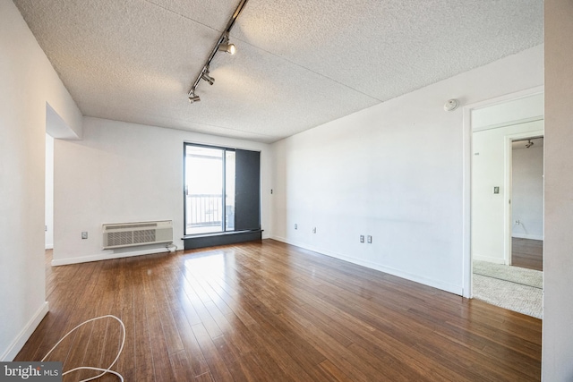 empty room featuring track lighting, a textured ceiling, wood finished floors, and a wall mounted AC