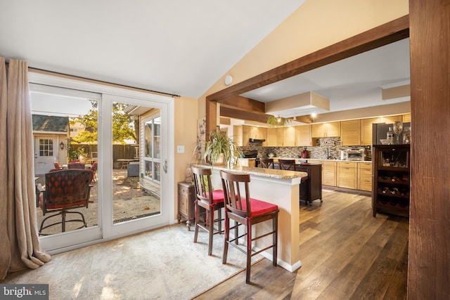 kitchen featuring decorative backsplash, dark hardwood / wood-style floors, a kitchen breakfast bar, kitchen peninsula, and light brown cabinetry