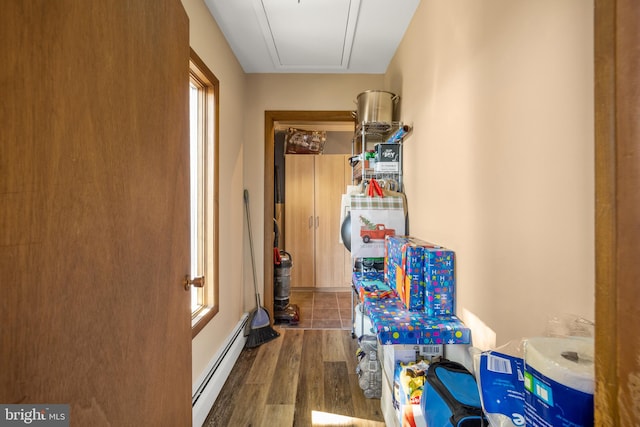 corridor with dark hardwood / wood-style flooring and a baseboard heating unit