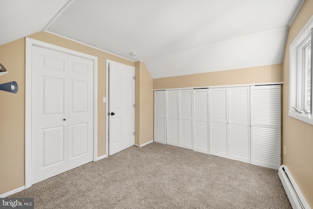 unfurnished bedroom featuring vaulted ceiling, a baseboard heating unit, and carpet floors