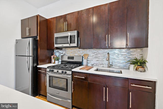 kitchen featuring tasteful backsplash, a sink, light countertops, appliances with stainless steel finishes, and dark brown cabinetry