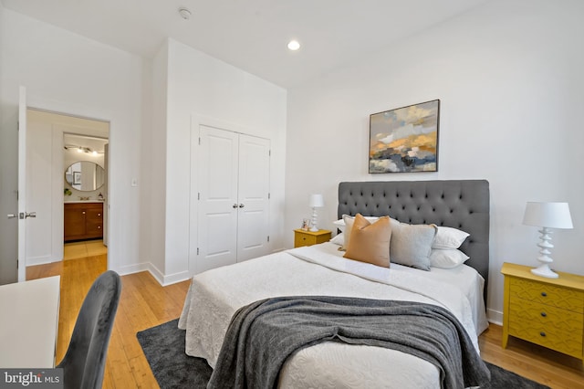 bedroom with a closet, baseboards, a sink, light wood finished floors, and recessed lighting