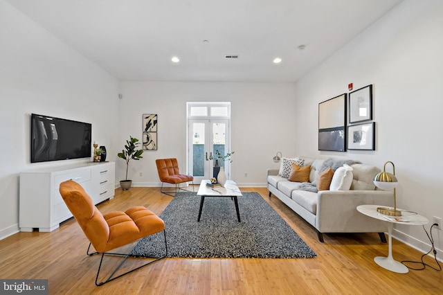 living area with light wood-type flooring, visible vents, baseboards, and french doors