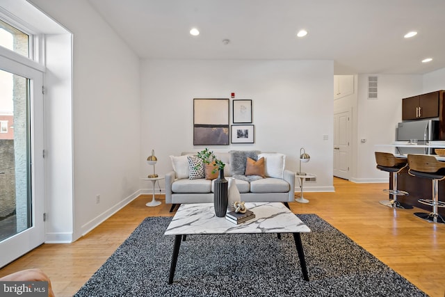 living room with light wood-type flooring, baseboards, and recessed lighting