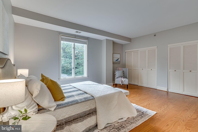 bedroom featuring multiple closets and light hardwood / wood-style flooring