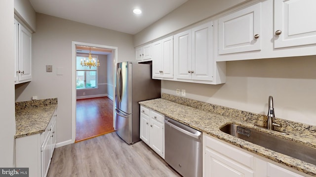 kitchen featuring appliances with stainless steel finishes, light wood-type flooring, light stone countertops, and white cabinetry