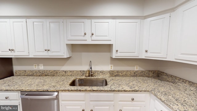 kitchen featuring stainless steel dishwasher, sink, and white cabinetry