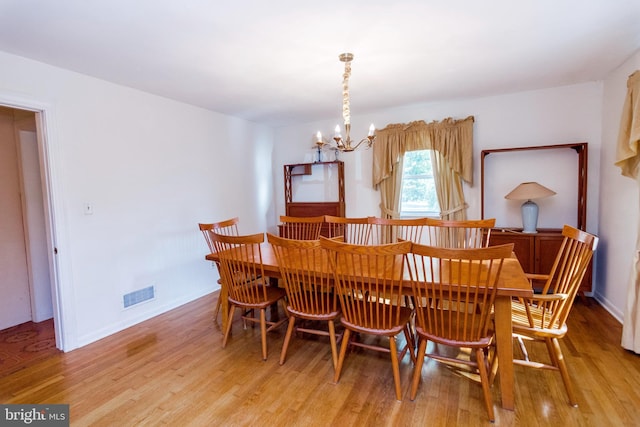 dining room with light wood finished floors, visible vents, and an inviting chandelier