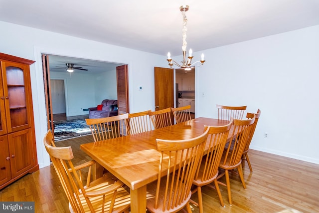 dining room with light wood-type flooring, baseboards, and ceiling fan with notable chandelier