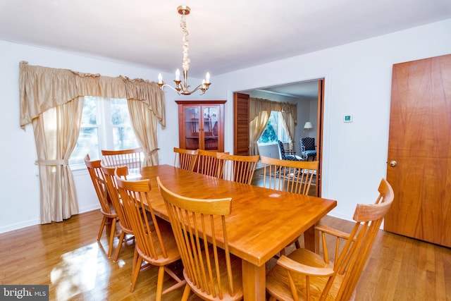 dining space featuring light wood-type flooring, baseboards, and an inviting chandelier