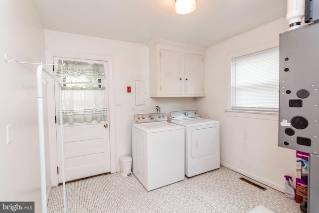 laundry area featuring electric panel, cabinets, and separate washer and dryer