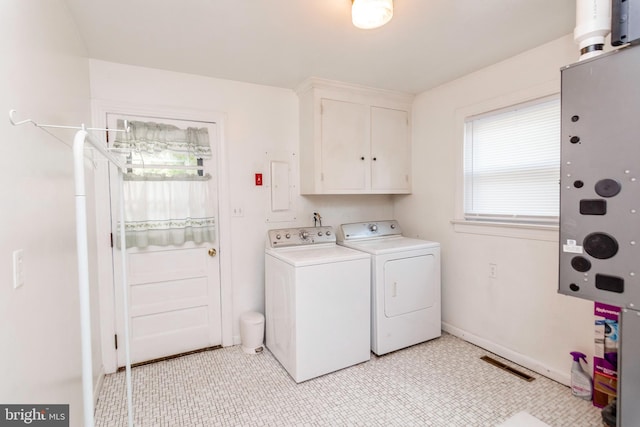 washroom with washing machine and dryer, a wealth of natural light, and cabinet space