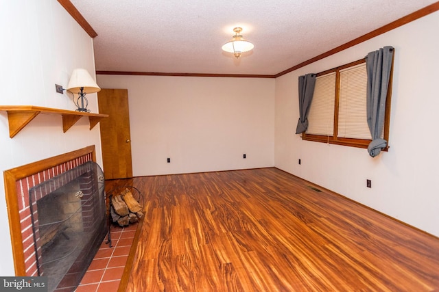 unfurnished living room with a textured ceiling, a tiled fireplace, hardwood / wood-style flooring, and crown molding