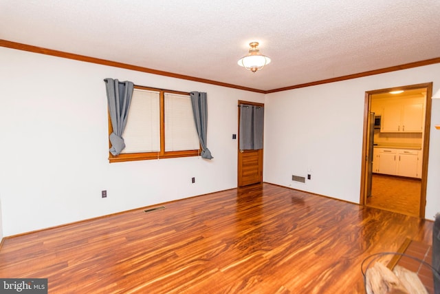 empty room with hardwood / wood-style flooring, a textured ceiling, and ornamental molding