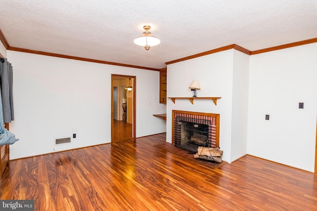 unfurnished living room featuring wood finished floors, visible vents, ornamental molding, and a brick fireplace