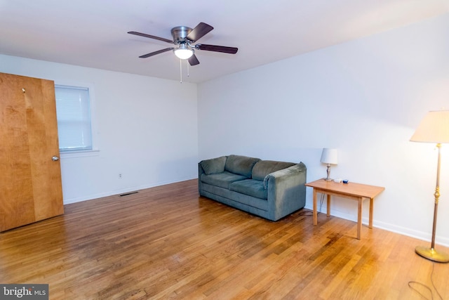 living area with wood-type flooring and ceiling fan