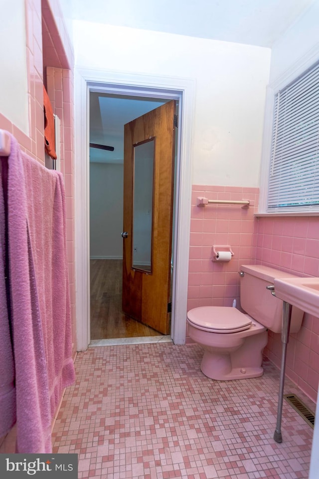 bathroom with tile walls, hardwood / wood-style flooring, and toilet