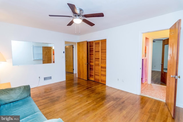 living room featuring baseboards, wood finished floors, visible vents, and ceiling fan