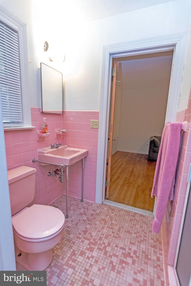 bathroom with tile walls, wood-type flooring, sink, and toilet